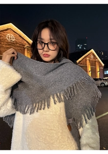 Detail of grey knitted scarf with long tassels showing thick warm texture for winter