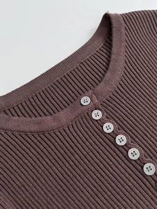 Close-up of ribbed knit texture and buttoned round neckline on brown slim sweater