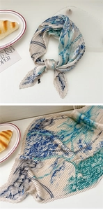 Detail view of cream-colored pleated scarf with blue abstract ink patterns and texture