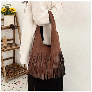 Deep brown faux suede shoulder bag with bohemian fringe detail shown on a model
