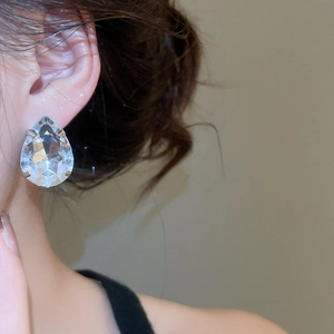 Macro view of teardrop crystal earring with high-quality metal claw setting on model