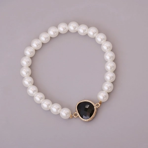 Elastic white pearl bracelet featuring a black heart charm with a gold-toned wavy border
