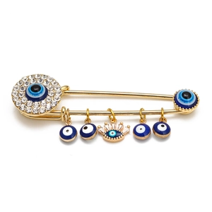 Macro detail of golden Evil Eye safety pin brooch with sparkling crystal rhinestones