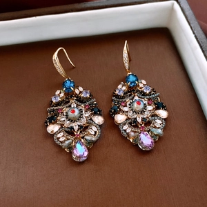 Detailed close-up of vintage gold drop earrings with colorful zircon and butterfly accents