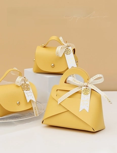 Detail of yellow leather wedding gift boxes with gold charms and elegant ribbon accents
