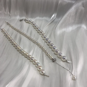 Three rows of lusterous pearl bracelets in varying sizes on a white satin fabric backdrop