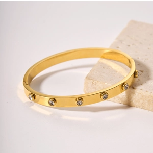 Detailed macro view of an 18k gold plated stainless steel bangle with inset cubic zirconia stones