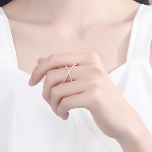 Detail of rose gold criss cross ring with micro-pave white zircon worn on finger