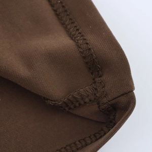Macro shot of precise stitching and hem detail on brown ruched jersey knit dress