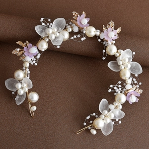 Macro detail of handmade bridal headband with gold leaves, white pearls and purple flowers