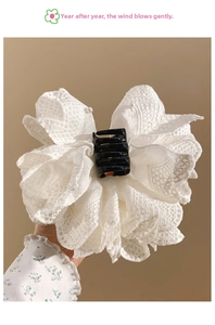 Macro shot of white lace bow hair claw with elegant pearl accents and black clip