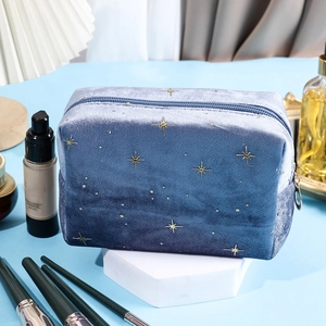 Blue velvet cosmetic bag with gold star pattern on a white hexagonal stand