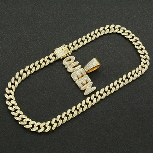 Close-up of golden iced-out Cuban chain necklace with sparkling QUEEN letter pendant