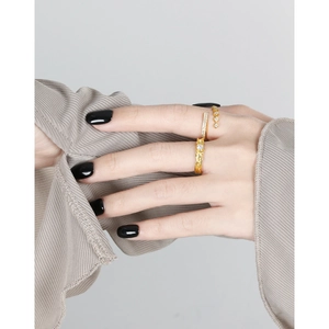 Elegant gold stacked rings set with white zircon stones on fingers with black nails