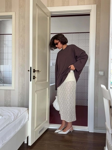 Oversize brown crewneck sweatshirt paired with a white lace midi skirt and heels