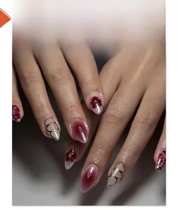 Detailed close-up of wine red floral almond press-on nails with golden geometric accents