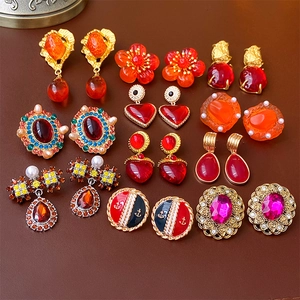 Flat lay of vintage gold-tone earrings with colorful gems and pearls on leather texture