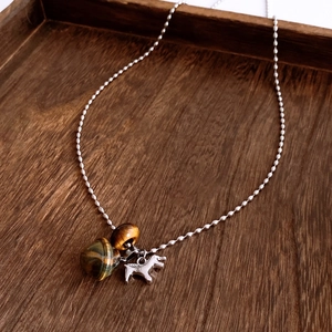 Macro detail of tiger eye stone beads and polished silver horse pendant on a ball chain