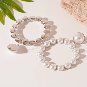 Détail de boucles d'oreilles créoles avec perles d'imitation et tiges en argent