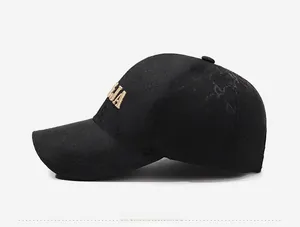 Side view of black baseball cap with golden embroidery and monogram pattern fabric