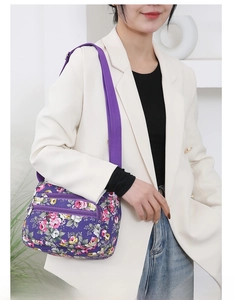 Detail view of the floral crossbody bag with multiple zippers and purple nylon strap