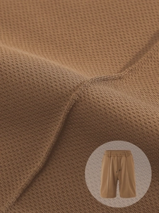 Detail of brown breathable pineapple knit texture and elastic drawstring waistband on shorts