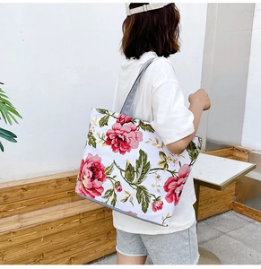 Close-up of a large canvas tote bag with red floral print and gray handles on stairs