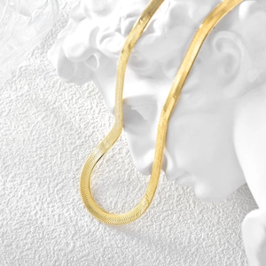 Elegant gold flat snake bone chain choker necklace displayed on a white marble bust