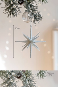 Dettaglio di una stella di Natale bianca glitterata da 15 cm appesa a un ramo di pino caldo