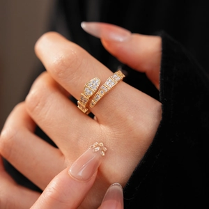 Close-up of golden snake ring set with white cubic zirconia worn on model finger