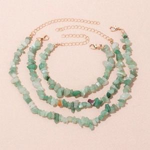 Detailed view of three natural green stone anklets with golden lobster clasps and chains