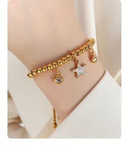 Detail of gold beaded bracelet with zircon starfish and round pendants on wrist