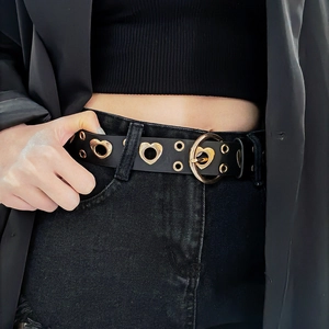 Detail of black punk leather belt with gold heart-shaped cutouts and round ring buckle