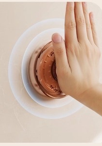 Detail of hand pressing a brown magnetic inverted toothbrush cup on marble surface