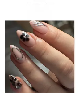Macro detail of almond press-on nails with black flower art and silver 3D metal lines