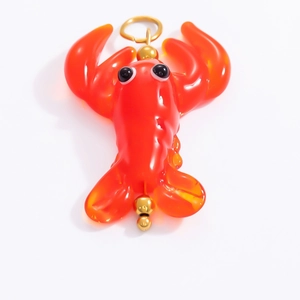 Macro shot of an orange glass lobster pendant with a golden loop for DIY jewelry