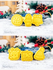 Baked golden Christmas cookies in snowman, tree, and reindeer shapes with X'mas text