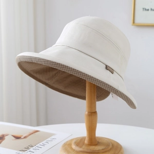 Détail d'un chapeau bob beige avec doublure à carreaux marron et texture fine en coton