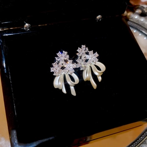 Detail of 14k gold plated earrings featuring zircon flowers and white bow tassels