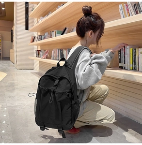 Seitenansicht des schwarzen Nylon-Rucksacks mit vielen Taschen in einer Bibliothek-Szene