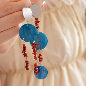 Bohemian silver drop earrings with blue resin discs and red coral beads on fabric