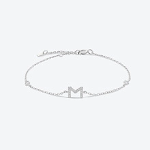 Macro detail of silver necklace featuring a sparkling letter M pendant with zircon stones