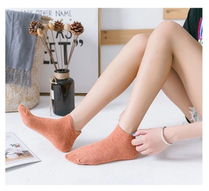 Detail of orange low cut cotton socks with cartoon dog embroidery on model feet