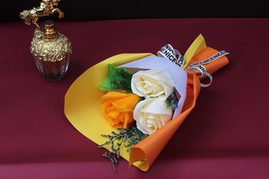 Close-up of artificial rose bouquet in orange and yellow wrap with elegant ribbons