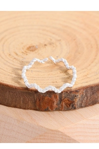Macro shot of silver twisted rope wave ring on a natural wood textured background