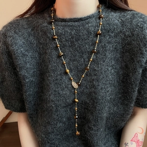 Detail of tiger eye beaded Y-necklace with gold leaf pendant on grey sweater