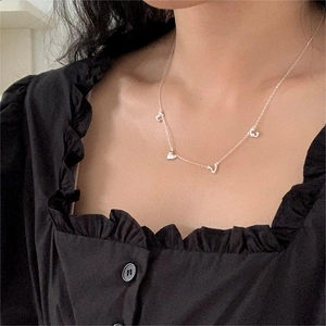 Close-up of minimalist S925 silver LOVE necklace with heart charms on model