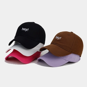 Macro detail of 'hey!' letter embroidery on various colored cotton baseball caps