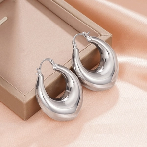 Detailed macro view of chunky silver teardrop hoop earrings on satin fabric