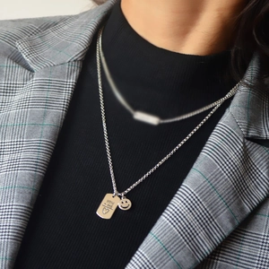 Close-up of silver long necklace with square YOU + ME heart pendant and smiley face charm